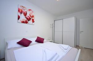 a white bedroom with a white bed with red pillows at Apartment Tribunj 16884b in Tribunj