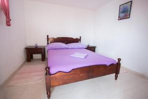 a bedroom with a wooden bed with purple sheets at Secluded fisherman's cottage Cove Spiljice, Brac - 17031 in Selca