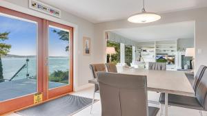 a dining room with a table and chairs with a view of the ocean at Deep Cove Retreat on the Ocean in North Saanich