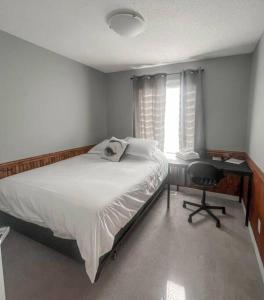 a bedroom with a bed and a desk and a window at Entire Home Near Calgary, Canmore & Banff Rocky Mountain Gateway in Cochrane