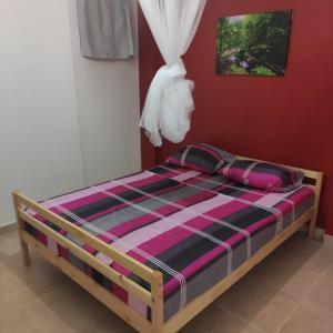 a bed in a room with a red wall at La Jandyra in Gros-Morne