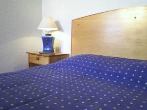 a bed with a blue comforter and a lamp on a table at Cabañas Barrachina, Punta de Tralca in El Quisco