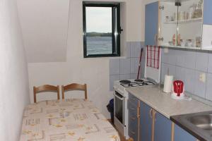 eine Küche mit einem Tisch, einem Herd und einer Spüle in der Unterkunft Apartments by the sea Orebic, Peljesac - 16883 in Orebić + 13 Fotos