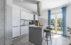 une cuisine avec des placards blancs et un bar avec des tabourets dans l'établissement Luxury villa with a swimming pool Vodnjan, Fazana - 16867, à Mednjan