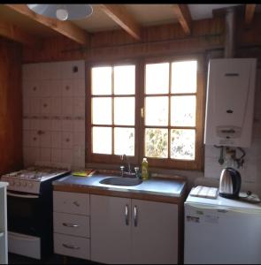 een keuken met een wastafel, een fornuis en ramen bij CABAÑA LOS MORROS in Ushuaia