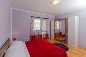 a bedroom with a bed with a red blanket and a mirror at Apartments by the sea Vinisce, Trogir - 16860 in Vinišće