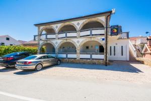 a building with two cars parked in front of it at Apartments with parking space Vir - 18540 in Vir