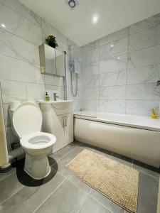 a bathroom with a toilet and a tub and a sink at Lovely 2 bedroom serviced apartment in London in London