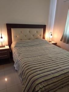 una camera da letto con un grande letto con una coperta a righe di Departamento en Nueva Córdoba - Patagonia 7 a Córdoba