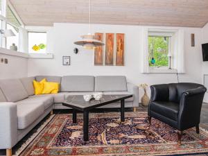 ein Wohnzimmer mit einem Sofa, einem Tisch und einem Stuhl in der Unterkunft Holiday home Grenaa XLII in Brøndstrup