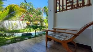 einen Schaukelstuhl auf einer Veranda mit Gartenblick in der Unterkunft Aqua Blue in Arugam Bay