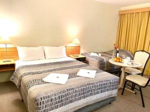 a hotel room with two beds and a table and chairs at Gateway Motor Inn in Narrandera