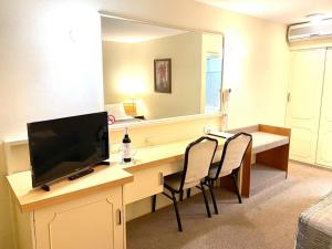 a hotel room with a television and a desk at Gateway Motor Inn in Narrandera