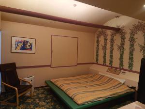 um quarto com uma cama e uma cadeira em キャッスル24 em Hanno