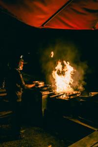 un hombre cocinando sobre un fuego en una parrilla en Otentic, Eco Tent Experience, en Grande Rivière Sud Est