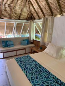 1 dormitorio con 2 camas y 2 ventanas en FARE TEMANEA en Papetoai