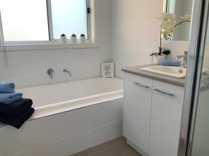 a white bathroom with a tub and a sink at METUNG 3 BEDROOM New House in Metung