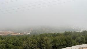 a foggy view of a mountain with trees and houses at Furnished house بيت مفروش ابو فارس in Ajloun