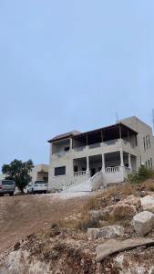 un edificio en una colina con coches estacionados frente a él en Furnished house بيت مفروش ابو فارس, en Ajloun