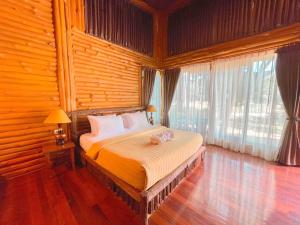 ein Schlafzimmer mit einem Bett in einem Zimmer mit Holzwänden in der Unterkunft Blues River Resort in Chao Lao Beach
