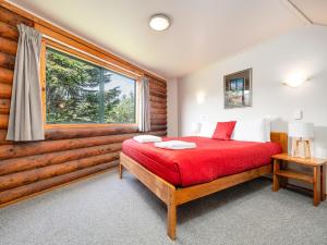 a bedroom with a red bed and a window at Shining Star Beachfront Accommodation in Hokitika