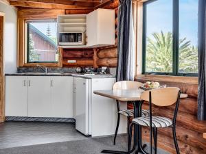 a kitchen with white cabinets and a table and chairs at Shining Star Beachfront Accommodation in Hokitika