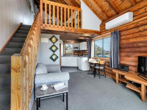 een woonkamer met een trap, een bank en een tv bij Shining Star Beachfront Accommodation in Hokitika