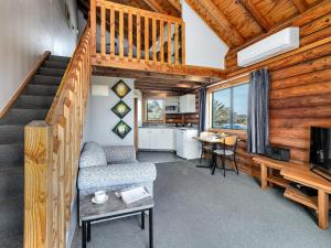 sala de estar con escalera, sofá y TV en Shining Star Beachfront Accommodation, en Hokitika