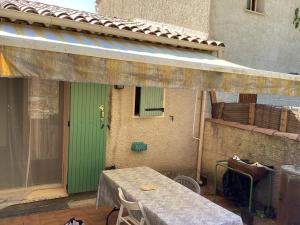 a patio with a table and a green door at Numéro 190 rue des moulins Nid douillet au cœur de la haute Provence vachéres in Reillanne