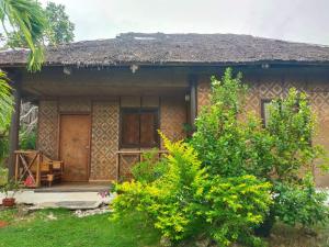 una casa con una porta in legno e alcuni cespugli di Allba's Homestay a Moalboal