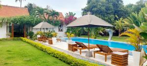 a patio with chairs and an umbrella next to a pool at The Edicha in Lovina