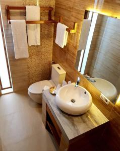 a bathroom with a sink and a toilet and a mirror at The Edicha in Lovina