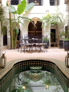 マラケシュにあるリヤド アル マモウネのテーブルと椅子付きの中庭のプールを提供しています。