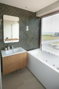 y baño con bañera, lavabo y espejo. en MARINIS Luxury Apartments - Svencelės Vėjai - 1st line by the Lagoon, en Svencelė