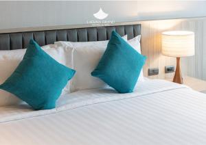 a white bed with two blue pillows on it at Laguna Grand Hotel & Spa Songkhla in Songkhla