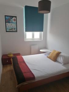- une chambre avec un lit blanc et une fenêtre bleue dans l'établissement L'Échappée Belle, à La Rochelle