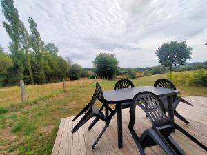 a black table and two chairs on a wooden deck at Le domaine des biches in Longueville