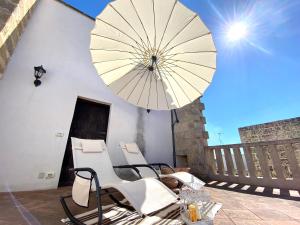 um pátio com cadeiras e um guarda-sol numa varanda em Ca Strignano Suite, Typical House em Castrignano del Capo