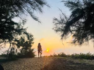 uma mulher parada numa praia a olhar para o pôr-do-sol em Secret Bay Panama em Arugam Bay