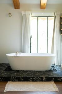a white bath tub sitting on a table next to a window at Hanahala Beramot - Boutique Suites in Moshav Ramot