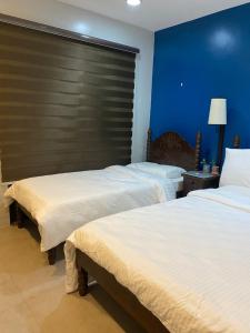 2 Betten in einem Hotelzimmer mit blauen Wänden in der Unterkunft Vivere Condominium in Vigan City