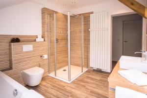ein Bad mit einer Dusche, einem WC und einem Waschbecken in der Unterkunft Hotel Großbach in Menzenschwand