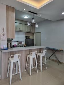 eine Küche mit weißen Stühlen und einer Theke in der Unterkunft 3R2B Entire Apartment Air-Conditioned by WNZ Home Putrajaya for Islamic Guests Only in Putrajaya