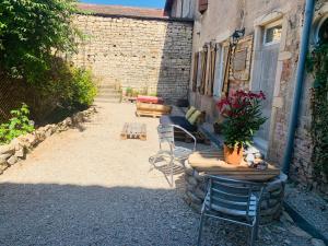 un patio avec une table et des chaises à côté d'un bâtiment dans l'établissement Le Chardon, à Chardonnay