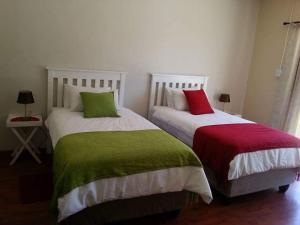 2 Betten mit grünen und roten Kissen in einem Zimmer in der Unterkunft Three Angelz Lodge in Queenstown