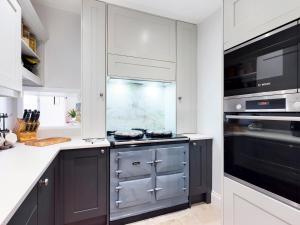 a kitchen with white cabinets and a stove top oven at Hackney House in Richmond +37 photos