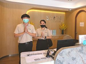 two men wearing masks standing in front of a desk at Sann Boutique Hotel in Chiang Rai