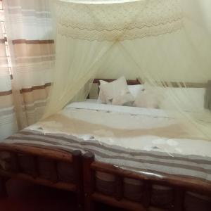 1 dormitorio con cama con dosel, sábanas y almohadas blancas en Dream jet suites, en Entebbe