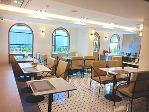 ein Restaurant mit Tischen, Stühlen und Fenstern in der Unterkunft Sann Boutique Hotel in Chiang Rai