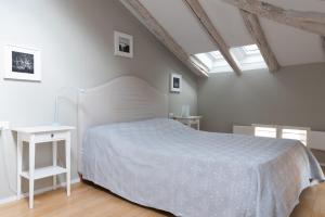 1 dormitorio con 1 cama con colcha blanca en Tribunali suite de charme, en Bolonia